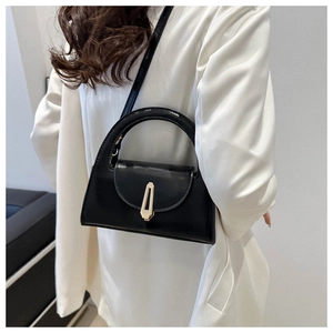 Minimalistische schwarze Handtasche mit goldener Schließe auf weißem Blazer
