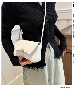 Close-up of white PU leather baguette bag with golden buckle on a fashion model