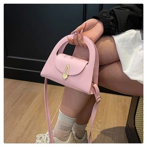 Detailaufnahme der rosa Ledertasche mit ausgeschnittenem Griff und goldenem Verschluss