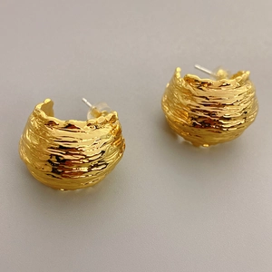 Minimalist gold-plated C-shaped earrings with irregular lava texture on grey background