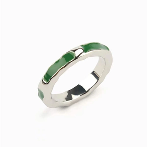Macro detail of silver plated brass ring featuring vibrant green enamel segment accents
