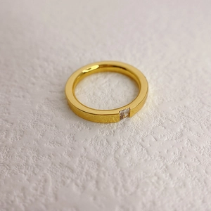 Minimalistischer Goldring mit quadratischem Kristallstein auf flacher Ringschiene