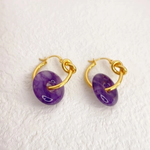 Detail of 18K gold brass hoop earrings featuring purple jade donut drop pendants