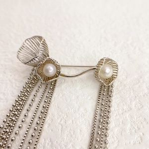 Elegant silver tassel brooch featuring double pearls and floral cage accents for coats