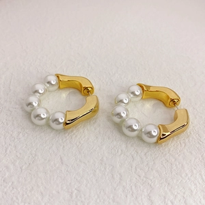 Golden beaded hoop earrings with white pearls in a modern irregular open-circle design