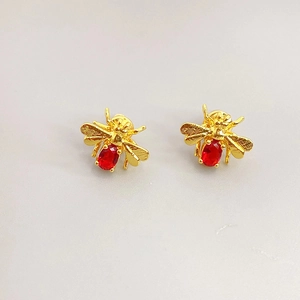 Detailed view of bee earrings featuring gold wings and a ruby-colored faceted stone