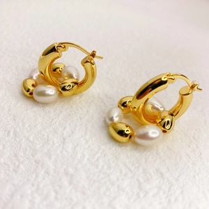 Créoles en laiton plaqué or 18K avec perles de culture et boules dorées sur fond blanc