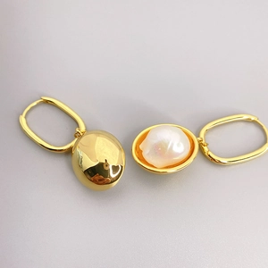 Vintage gold U-shape earrings featuring natural baroque pearl pendants on light background