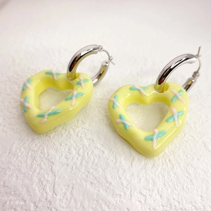 Detailed macro of yellow heart drop earrings with colorful cross-stitch resin textures