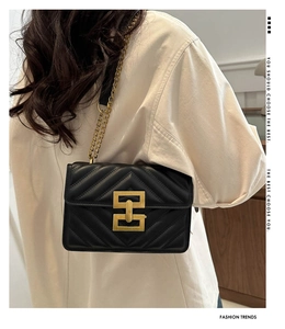 Rear view of a chic black quilted crossbody bag with a gold chain strap on a model