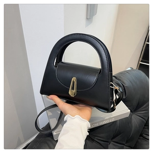 Detailansicht der schwarzen halbkreisförmigen Handtasche mit goldenem geometrischem Verschluss