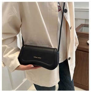 Detail of matte black leather handbag with gold Miss mini logo and wavy flap design