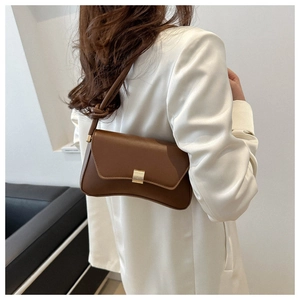 Detail of a minimalist dark brown leather crossbody bag featuring a golden buckle and knot strap