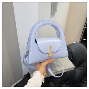 Detail einer hellblauen Lederhandtasche mit goldenem Verschluss und rundem Tragegriff
