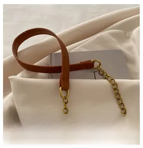 Detail of a brown leather shoulder strap with a polished golden metal chain for a handbag