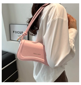 Detail of light pink leather underarm bag featuring minimalist Miss mini logo and knot strap