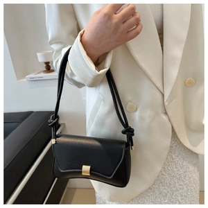 Detailed view of black leather shoulder bag with gold buckle and knotted strap