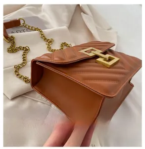 Detailed close-up of brown V-quilted leather bag with gold geometric lock and chain strap