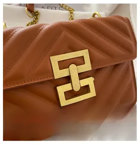 Detail of a brown V-quilted leather bag featuring a gold geometric lock and chain strap