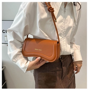 Detail of caramel brown matte leather mini bag with Miss mini logo and knotted shoulder strap