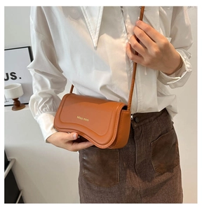 Detail of an orange Miss Mini crossbody bag with wavy curve flap and golden logo