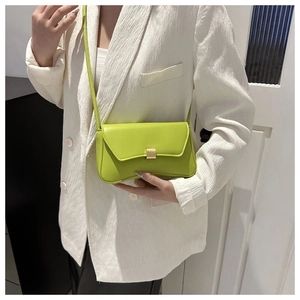 Detail showing neon green crossbody bag with leather texture and matte gold buckle