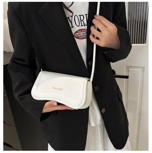 Detail of white PU leather crossbody bag with unique wavy bottom and gold branding