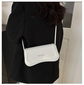 Detailed back view of a white leather mini shoulder bag with gold Miss mini text on a blazer
