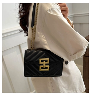 Detail of black quilted leather shoulder bag with gold geometric interlocking buckle