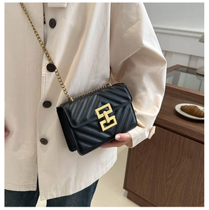 Close-up of black quilted small square bag with V-shaped stitching and gold chain strap
