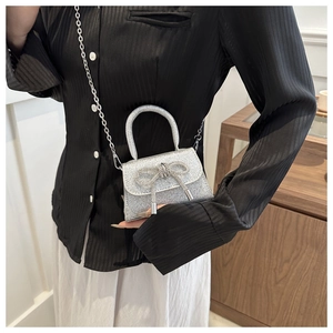 Detail of silver glitter mini bag with rhinestone bow and elegant metal chain strap