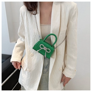 Detail of sparkling green mini crossbody bag with crystal bow and silver metal chain strap