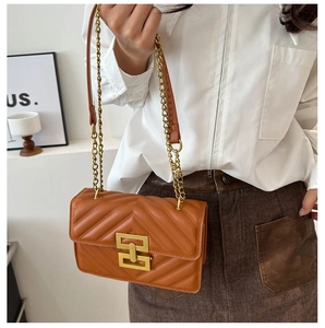 Detail of caramel brown quilted bag with gold chain strap and interlocking metal clasp