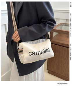 Detail of beige cylinder crossbody bag with camellia print and striped textile strap