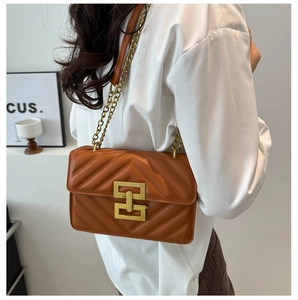 Detail view of brown quilted crossbody bag with gold chain strap and metal lock