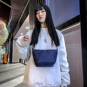 Bolso tipo cubo minimalista de nailon azul marino con correa ajustable llevado por modelo
