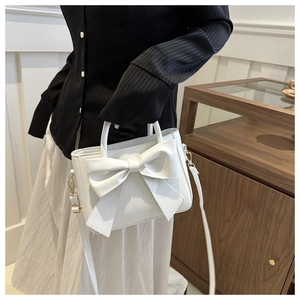 White PU leather bucket bag with a large bow detail and detachable shoulder strap on model