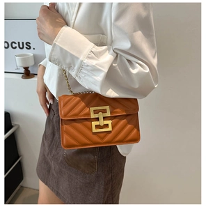 Close-up of orange quilted square bag with V-shaped stitching and golden H-lock