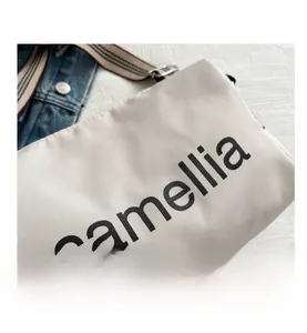 Detail of adjustable striped woven strap and camellia print on beige canvas bag