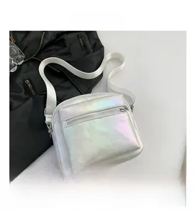 Detalle de bolso bandolera plateado iridiscente con doble cremallera y correa tejida