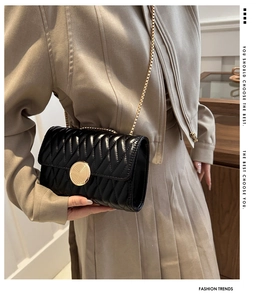 Détail du sac matelassé noir avec coutures en V et boucle dorée ronde en métal