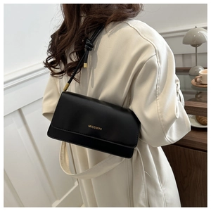 Detail of black leather crossbody bag with gold logo and dual shoulder strap options
