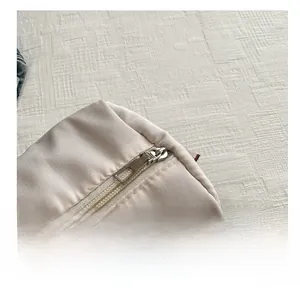 Macro detail of high-quality smooth silver metal zipper on beige oxford fabric bag