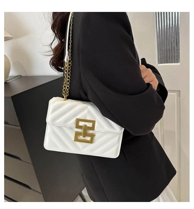 White quilted crossbody bag with gold chain strap shown on model in black blazer