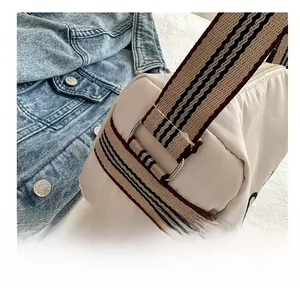 Detail of metal D-ring buckle and colorful striped woven strap on canvas tote bag