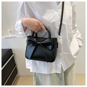 Mini black bow handbag in matte PU leather with gold hardware and crossbody strap
