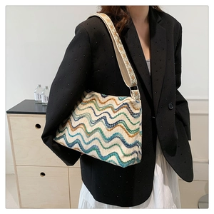 Détail du sac seau en toile rayée bohème avec une large bandoulière brodée portée