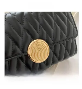 Gros plan d'un sac en cuir matelassé noir avec un fermoir doré circulaire texturé