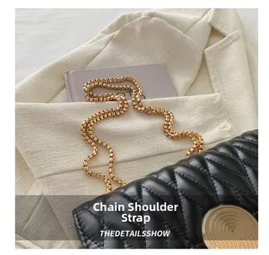 Détail macro du sac bandoulière matelassé noir avec chaîne dorée et boucle métallique