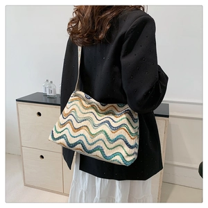 Détail d'un sac cabas en laine bohème aux motifs de vagues colorées sur un mannequin